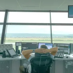 Kontroler lotów w wieży obserwuje monitory. Chcesz wiedzieć, jak zostać kontrolerem lotów? To praca pełna odpowiedzialności.
