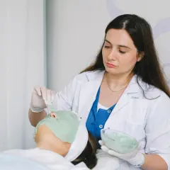 Kosmetyczka nakłada maskę na twarz klientki. Zastanawiasz się, ile zarabia kosmetyczka?