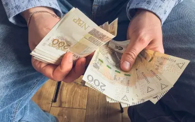 Ręce trzymające stos banknotów 200 zł. To może być wynagrodzenie za urlop, które pozwoli na zasłużony odpoczynek.