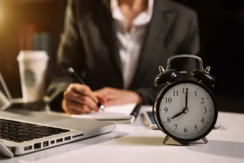 Budzik pokazuje 8:00, a osoba pisze w notatniku. Ile godzin pracy jeszcze przed nią?