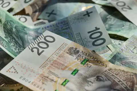 Złote banknoty 100 i 200 zł, symbolizujące średnią pensję w Polsce.