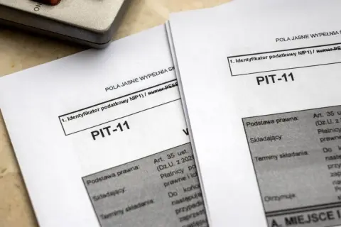 Dokumenty PIT-11 leżą obok kalkulatora. Jak rozliczyć PIT-11? To pytanie zadaje sobie wielu podatników.