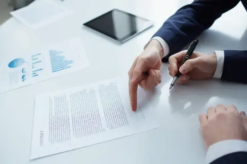 Dwie osoby omawiają umowę, analizując wykresy i dane. Kluczowa jest tu współpraca B2B.