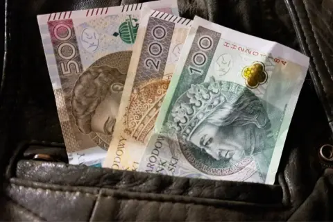 Polskie banknoty 500, 200 i 100 zł w kieszeni kurtki. Czy to wystarczy na najniższą krajową netto na godzinę?