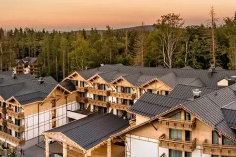 Nowy hotel w górach, oferujący zatrudnienie, otoczony lasem.