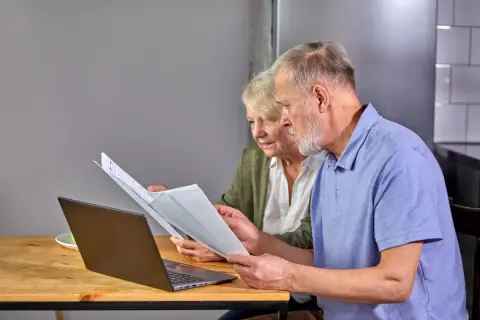 Para seniorów analizuje dokumenty przy laptopie. To przykład ulgi dla seniora w PIT-37.