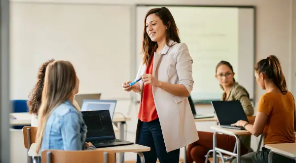 Nauczycielka wyjaśnia studentom, jak zostać nauczycielem, prowadząc lekcję w sali komputerowej.