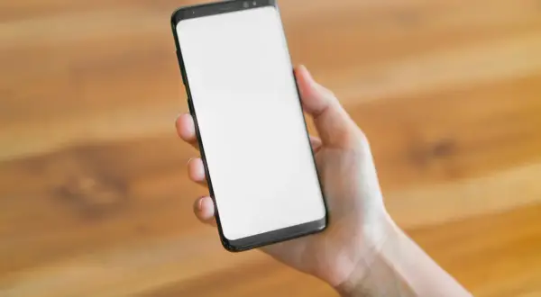 Dłoń trzyma smartfon z pustym ekranem. Czekam na ważny telefon, bo mam dyżur.