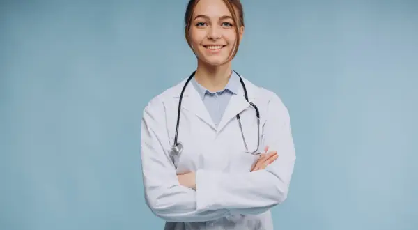 Uśmiechnięta lekarka w białym kitlu ze stetoskopem, zastanawia się, ile zarabia psychiatra.