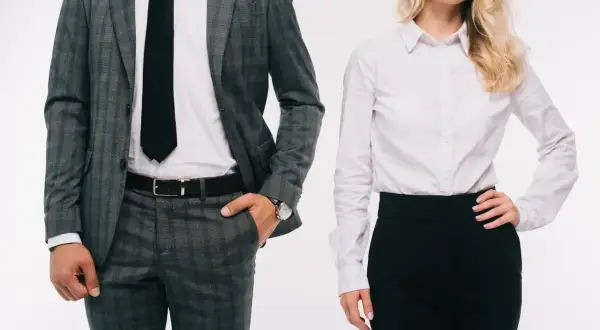 Elegancki mężczyzna w garniturze i kobieta w białej koszuli i czarnej spódnicy, prezentujący profesjonalny dress code.