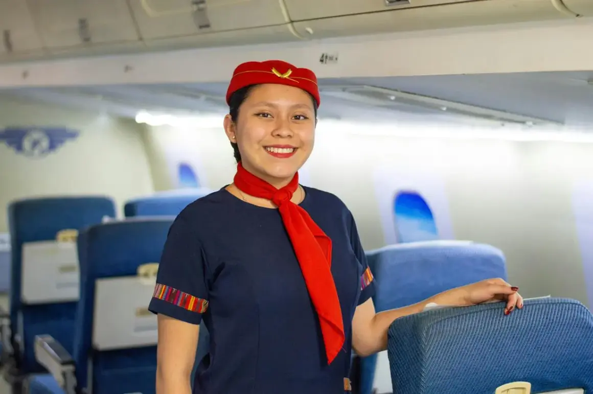 Uśmiechnięta stewardessa w czerwonym beretku i z szalikiem, gotowa do lotu. Marzysz, jak zostać stewardessą?