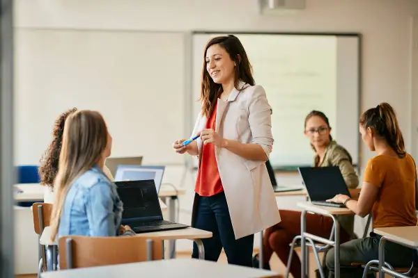 Nauczycielka wyjaśnia studentom, jak zostać nauczycielem, prowadząc lekcję w sali komputerowej.